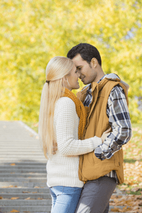 A woman about to kiss her boyfriend in the park