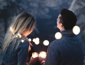 a man and woman holding candles and looking at the night's sky