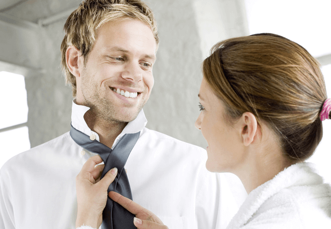 a woman in a relationship with her boyfriend helping him with his tie