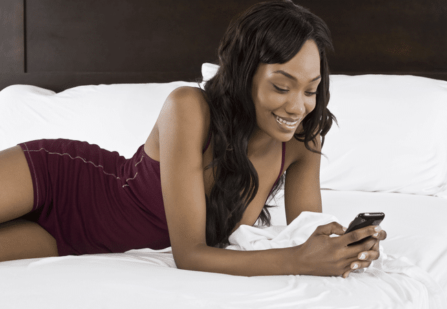 a woman lying on a bed sending a text message