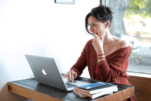 a woman sitting at her computer thinking how to attract a Scorpio man online